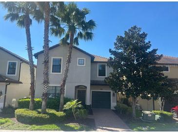 Charming two-story home with a manicured lawn, palm trees, and a private garage at 5520 Solterra Cir, Davenport, FL 33837