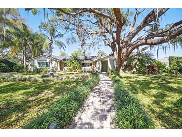 Charming single-story home featuring a lush front yard, mature oak tree, and inviting walkway at 703 Valencia Shores Dr, Winter Garden, FL 34787