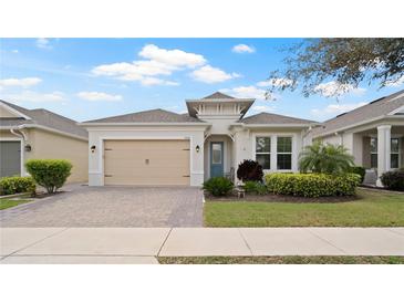 Charming single-story home with a paver driveway, tan garage door, and well-manicured landscaping at 7928 Hanson Bay Pl, Kissimmee, FL 34747
