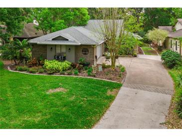 Aerial view of charming home featuring lush green lawn, mature trees and a paved driveway at 106 Waterwood Dr, Yalaha, FL 34797