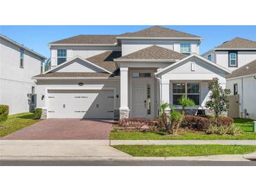 Charming two-story home with a brick driveway, manicured lawn and gray exterior at 14399 Wabasso Loop, Winter Garden, FL 34787