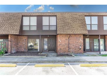 Exterior view of a two-story townhome featuring brick accents, a textured roof and parking spots at 1836 N Crystal Lake Dr # 104, Lakeland, FL 33801