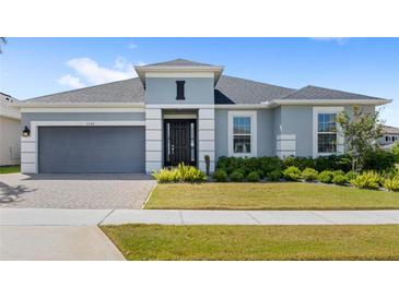 Charming single-story home featuring a well-manicured lawn, neutral paint, gray garage door, and a brick-paved driveway at 3347 Hanging Tide St, Winter Garden, FL 34787