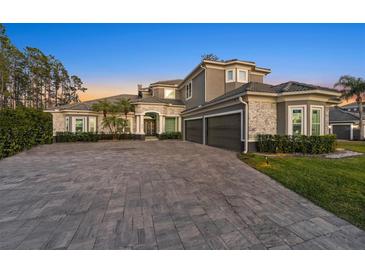 Elegant two-story home with stone accents, a three-car garage, and a large driveway at 4205 Clarice Ct, Windermere, FL 34786