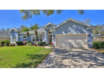 Charming single-story home featuring a well-manicured lawn, attached garage, and palm tree accents at 5776 Falling Tree Ln, Port Orange, FL 32127