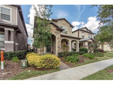 Charming two-story home featuring a stone facade, well-manicured landscaping, and inviting front porch at 7112 Enchanted Lake Dr, Winter Garden, FL 34787