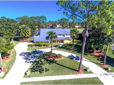 Expansive home featuring mature landscaping, a circular driveway, and a screened-in pool at 932 Pelican Bay Dr, Daytona Beach, FL 32119