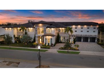 Stunning exterior view of a luxury home with manicured landscaping and a paver driveway at sunset at 1148 Grand Traverse Pkwy, Reunion, FL 34747