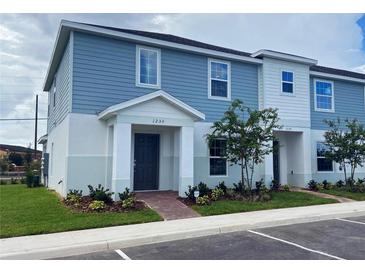 Charming two-story townhome featuring a blue exterior with well manicured landscaping at 1234 Sand Torch Cir, Davenport, FL 33837