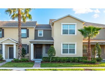 Two-story townhome showcases a landscaped front yard, mature palms, and neutral color palette at 12862 Strode Ln, Windermere, FL 34786