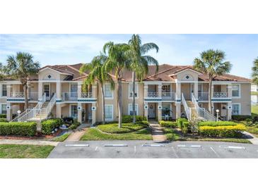 Inviting condo exterior featuring a tile roof, palm trees, and manicured landscaping at 13852 Timberbrooke Dr # 203, Orlando, FL 32824