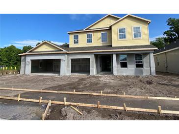 Two-story home featuring three-car garage and light yellow clapboard second story under a blue sky at 2430 Francisco Art Ct, Oviedo, FL 32765