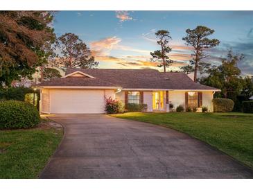 Charming brick home featuring a well-maintained lawn, mature trees, and a long driveway leading to an attached garage at 425 N Pine Meadow Dr, Debary, FL 32713