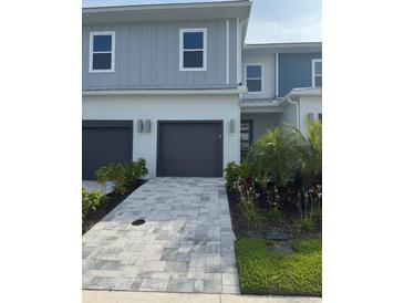 Charming home featuring a two-car garage, gray brick driveway, and well-manicured landscaping at 7810 Spectrum Dr, Kissimmee, FL 34747