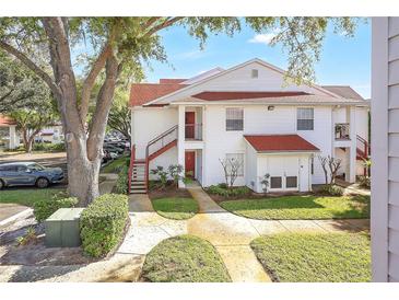 Inviting two-story condo featuring red stairs, mature landscaping, and assigned parking at 11568 Westwood Blvd # 1021, Orlando, FL 32821