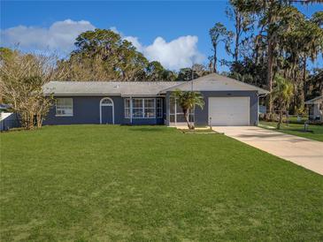 Charming single-story home with a lush green lawn and attached two-car garage at 11847 Ocklawaha Dr, Leesburg, FL 34788