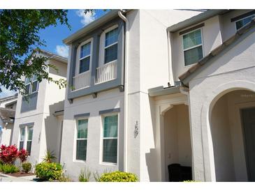 Charming two-story home with white exterior, gray trim, manicured landscaping, and a welcoming front entrance at 159 Captiva Dr, Davenport, FL 33896