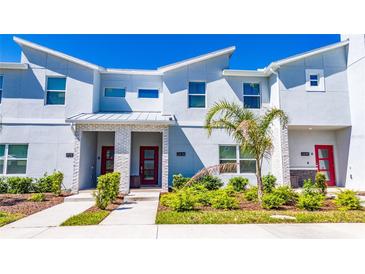 Stylish townhome featuring brick accents, manicured landscaping, and a vibrant red front door, enhanced by a clear blue sky at 2636 Reading Trl, Kissimmee, FL 34746