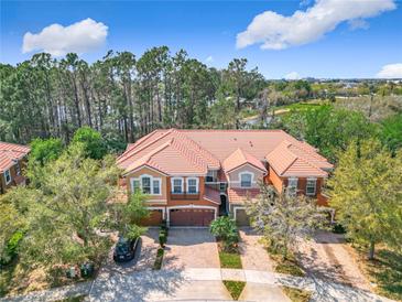 Beautiful shot of the exterior elevation with an orange tile roof, surrounded by lush trees, and well manicured lawn at 4952 Matteo Trl, Orlando, FL 32839
