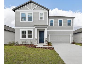 Charming two-story home featuring a gray exterior, well-manicured lawn, and attached two-car garage at 5719 Cattle Ranch Dr, St Cloud, FL 34771