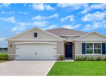 Charming one-story home features a two-car garage, inviting blue front door, and well-manicured lawn at 717 Squires Grove Dr, Winter Haven, FL 33880