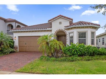 Charming home with a red tile roof, well-maintained landscaping, and a brick driveway leading to a two-car garage at 10257 Henbury St, Orlando, FL 32832