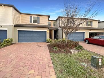 Townhome with blue garage doors, brick driveway, and landscaping at 987 Desert Candle Dr, Ocoee, FL 34761