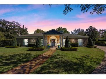 Charming brick home with manicured lawn, brick pathway, and lush landscaping, creating inviting curb appeal at 1600 Barcelona Way, Winter Park, FL 32789