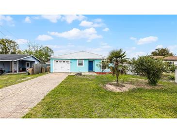 Charming light blue home featuring a single car garage and beautiful green lawn at 19624 E Umatilla Blvd, Umatilla, FL 32784