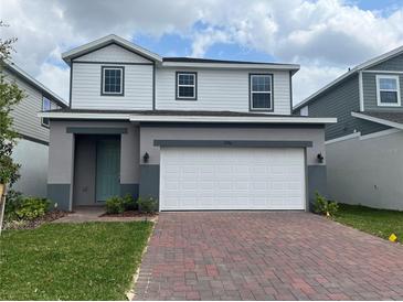 Charming two-story home featuring a red brick driveway and a two-car garage at 1996 Heart Lake Dr, Groveland, FL 34736