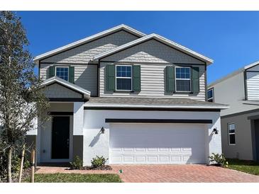 Charming two-story home featuring a two-car garage, gray siding and green shutters at 2000 Heart Lake Dr, Groveland, FL 34736