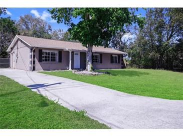 Charming single-story home boasts a well-manicured lawn, mature tree, and a long driveway leading to the front entrance at 2102 Nedra Ave, Deltona, FL 32725