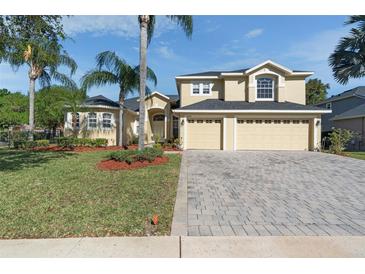 Charming home featuring a three-car garage, well-manicured lawn, and lush tropical landscaping at 2523 Water Valley Dr, St Cloud, FL 34771