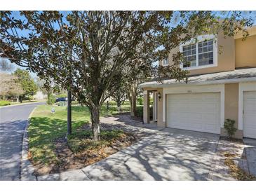 Charming condo exterior with attached garage and well-maintained landscaping, nestled beneath a beautiful mature tree at 2679 Metro Sevilla Dr # 101, Orlando, FL 32835
