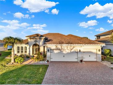 Beautiful single-story home with a tile roof, three-car garage and well manicured lawn and brick driveway at 3707 Paradiso Cir, Kissimmee, FL 34746
