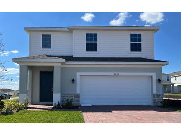 Two-story home featuring brick accents, an attached two-car garage, and a covered front entry at 7020 Rolling Leaf Dr, Groveland, FL 34736