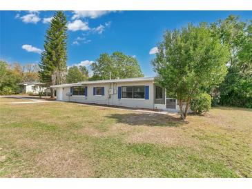 Charming single-story home features a manicured lawn and quaint blue shutters at 1203 Judy Ave, Tavares, FL 32778