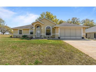Charming single-story home features a well-manicured lawn, arched windows, and attached two-car garage at 2011 Oakbend Dr, Eustis, FL 32726
