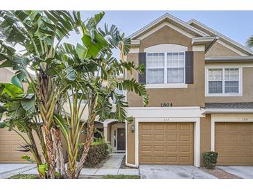 Inviting two-story townhome with a single-car garage and lush tropical landscaping at 2804 Polvadero Ln # 107, Orlando, FL 32835