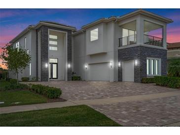 Stunning two-story home showcasing a modern design with stone accents and a spacious brick driveway at 942 Jack Nicklaus Ct, Kissimmee, FL 34747
