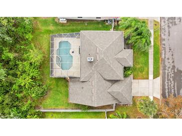 Aerial view of a home with a screened-in pool, lush landscaping, and a well-maintained gray roof at 13325 Falcon Pointe Dr, Orlando, FL 32837