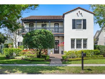 Charming two-story home with a stucco exterior, balcony, dark shutters, and well-manicured landscaping at 4457 Anson Ln, Orlando, FL 32814