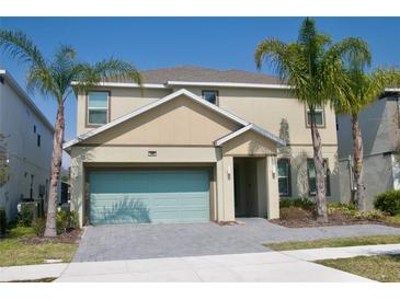 Two-story home featuring a two-car garage, with a charming entryway, and complemented by lush palm trees at 4489 Monado Dr, Kissimmee, FL 34746