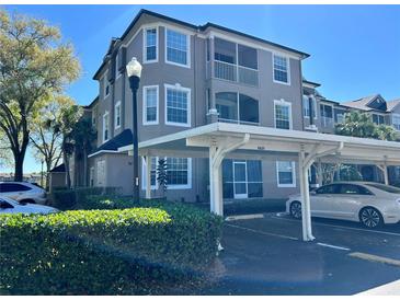 Condominium exterior featuring a carport and multiple stories with large windows and screened in patio at 7109 Yacht Basin Ave # 430, Orlando, FL 32835