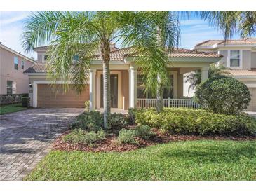 Charming two-story home featuring a brick driveway, lush landscaping, and a welcoming covered front porch at 11754 Barletta Dr, Orlando, FL 32827