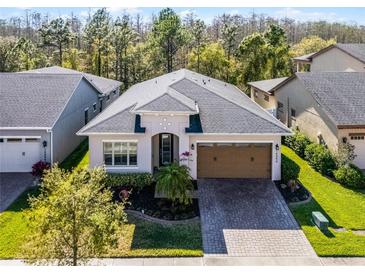 Beautiful single-story home featuring manicured landscaping, brick-paved driveway, and a two-car garage at 14090 Alafaya Oak Bnd, Orlando, FL 32828