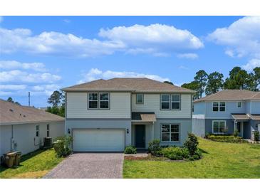 Charming two-story home featuring a manicured lawn and brick driveway at 17319 Million Lakes Ct, Clermont, FL 34714