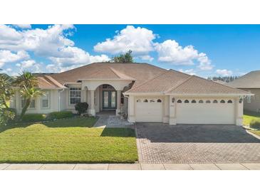 Inviting single story home showcasing a manicured lawn, mature landscaping, and a three car garage at 2509 Chapala Dr, Kissimmee, FL 34746