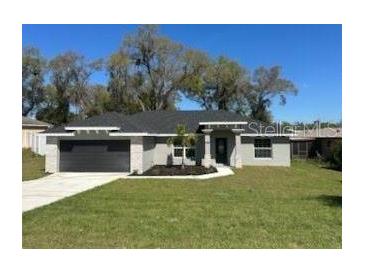 Charming single-story home featuring a well-manicured lawn, a two-car garage, and attractive stone accents on the facade at 1055 W French Ave, Orange City, FL 32763