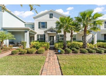 Charming home featuring lush landscaping, a brick walkway, and beautiful palm trees at 11844 Pulitzer Pl, Orlando, FL 32832